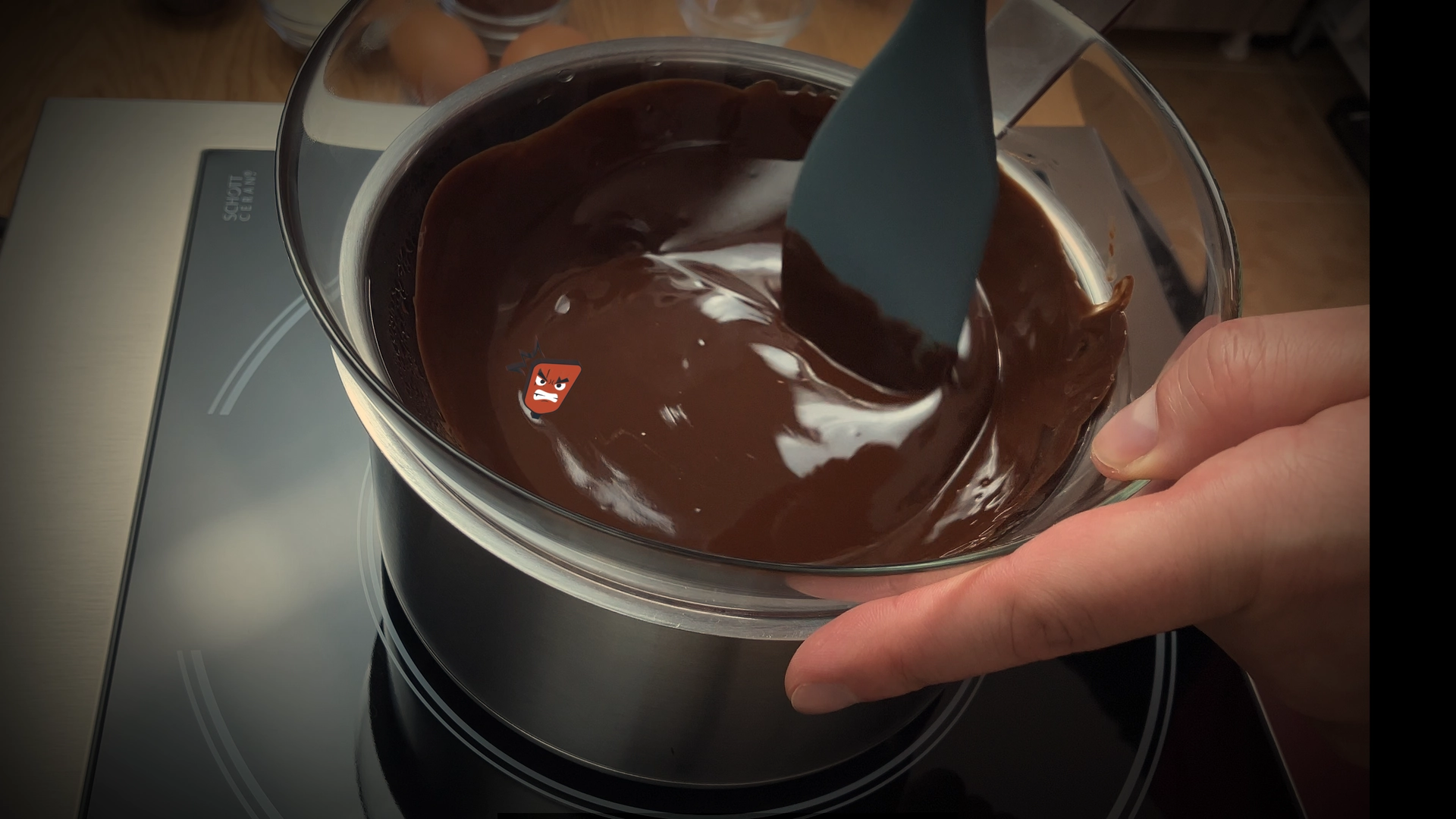 Melting and stirring chocolate and butter in a heatproof bowl over simmering water for brownie batter preparation.