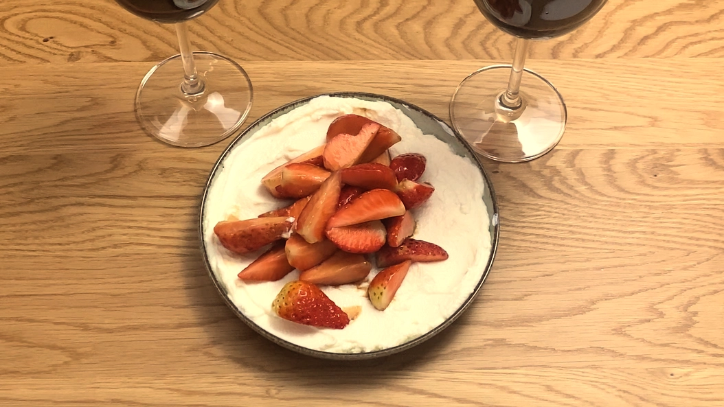 A white bowl filled with creamy white ricotta, topped with sliced fresh strawberries, a drizzle of honey and balsamic glaze, and garnished with fresh mint leaves.