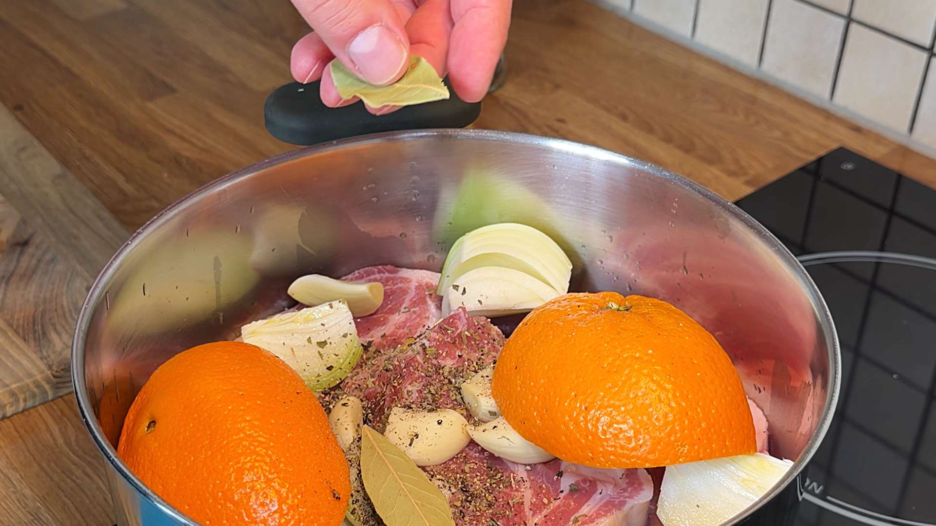 Raw pork shoulder with oranges, onions, and spices in a pot for carnitas.