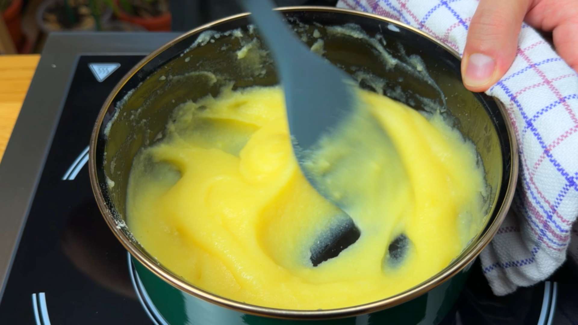 A pot of smooth, cooked corn flour polenta being stirred with a silicone spatula.