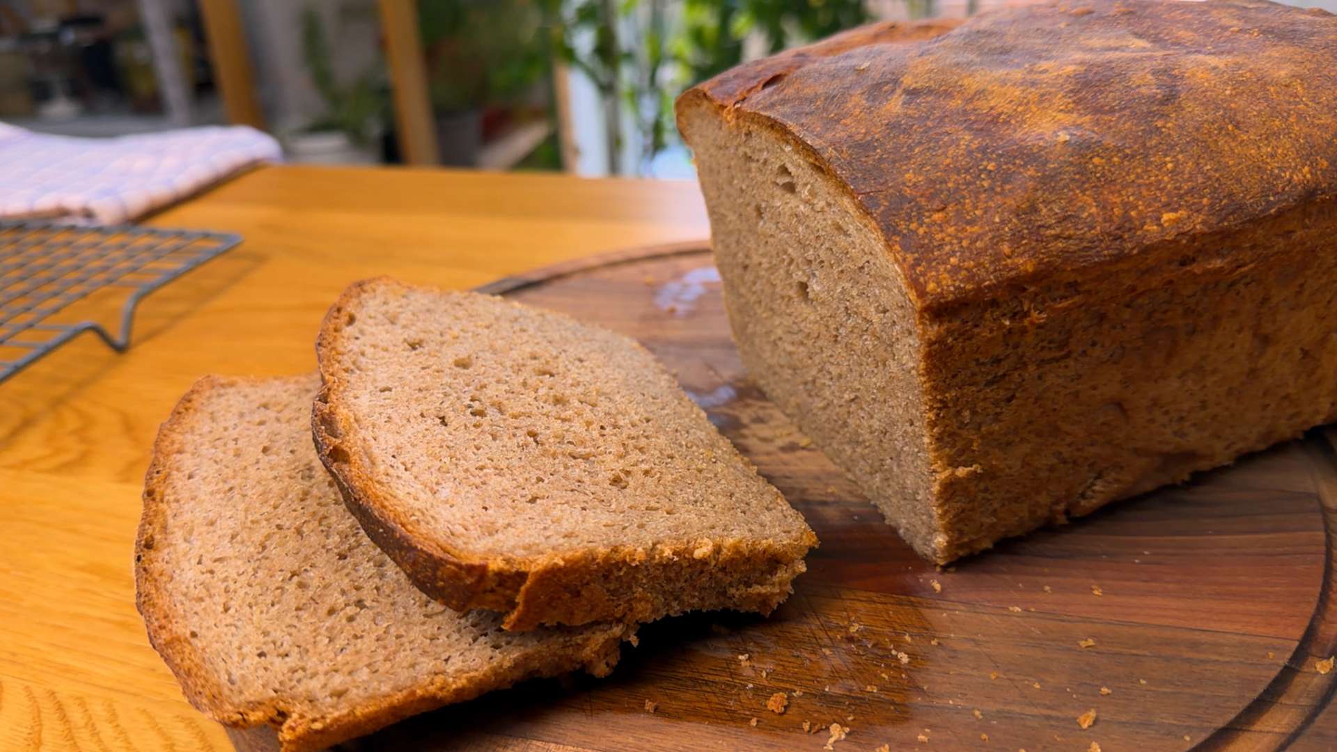 A freshly baked whole wheat bread loaf on a cutting board with two slices cut off, showing its soft texture.