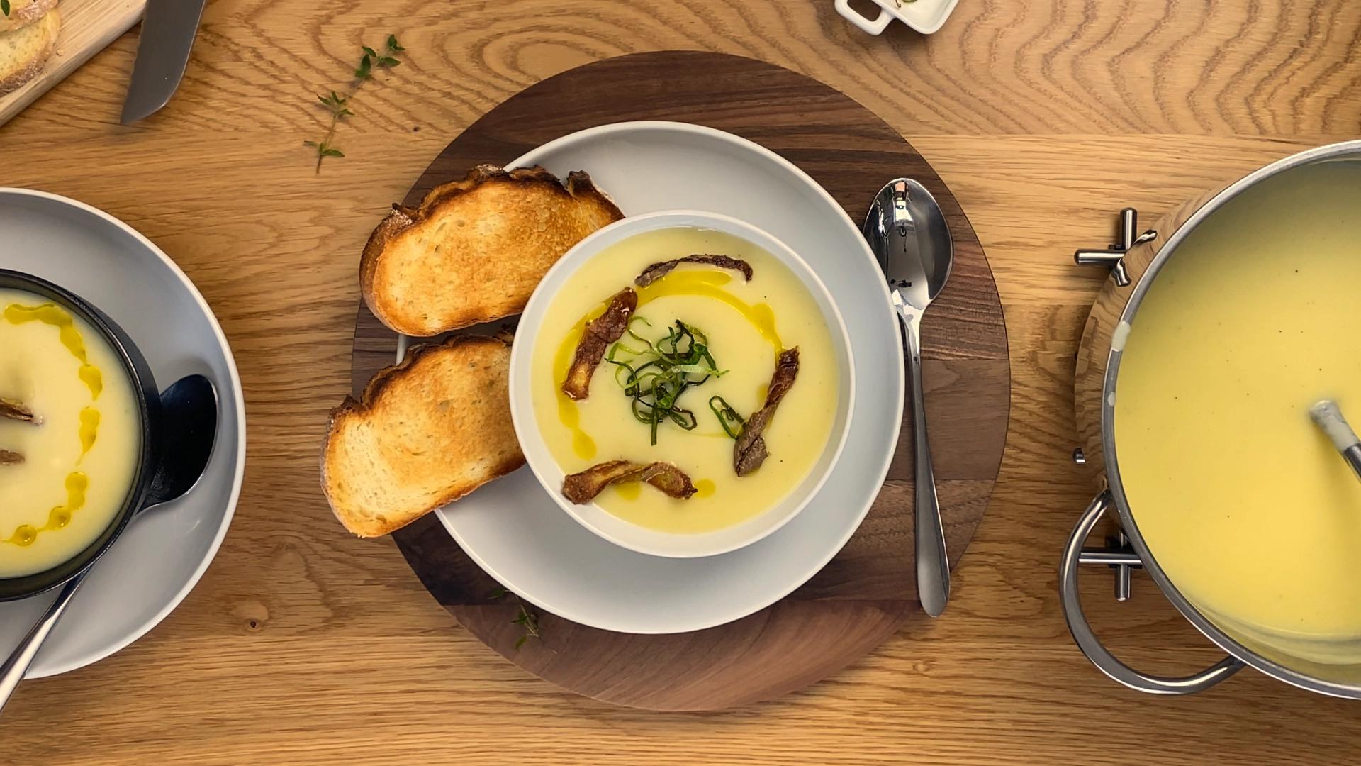 Creamy potato leek soup topped with fresh herbs and cracked black pepper in a rustic bowl.