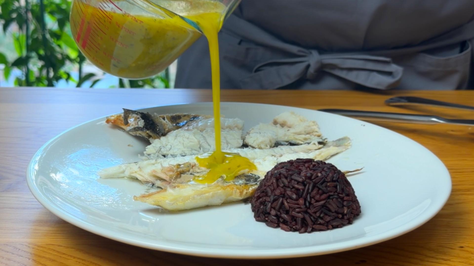 Sos od limuna i peršuna preliva se preko pečene orade iz rerne servirane sa crnim pirinčem.