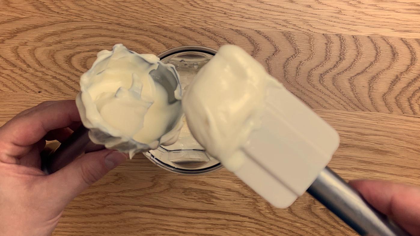 No-egg mayonnaise in a jar with creamy texture on spoon.