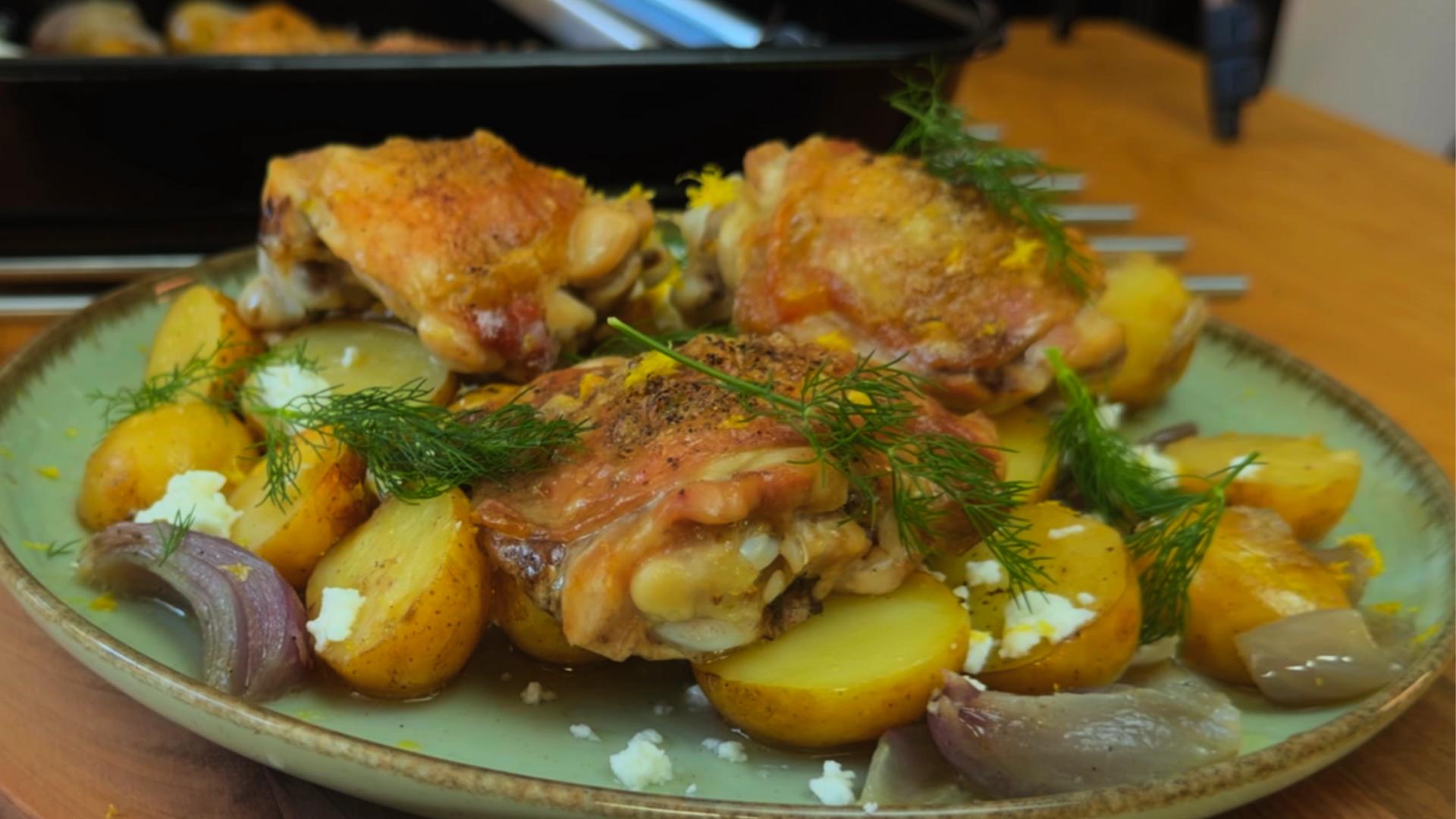 Roasted chicken thighs with baby potatoes, dill, feta cheese, and tender onions served on a rustic plate.