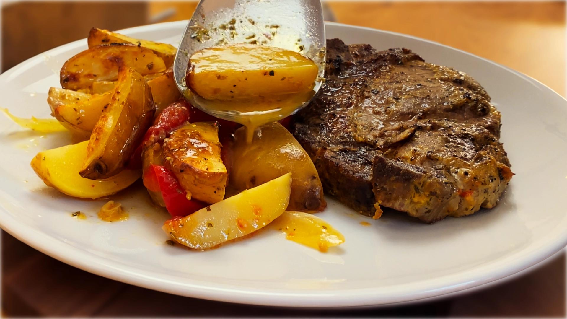 Close-up of golden oven-baked pork with roasted potatoes and vegetables in a baking dish, lightly caramelized and glistening with juices.